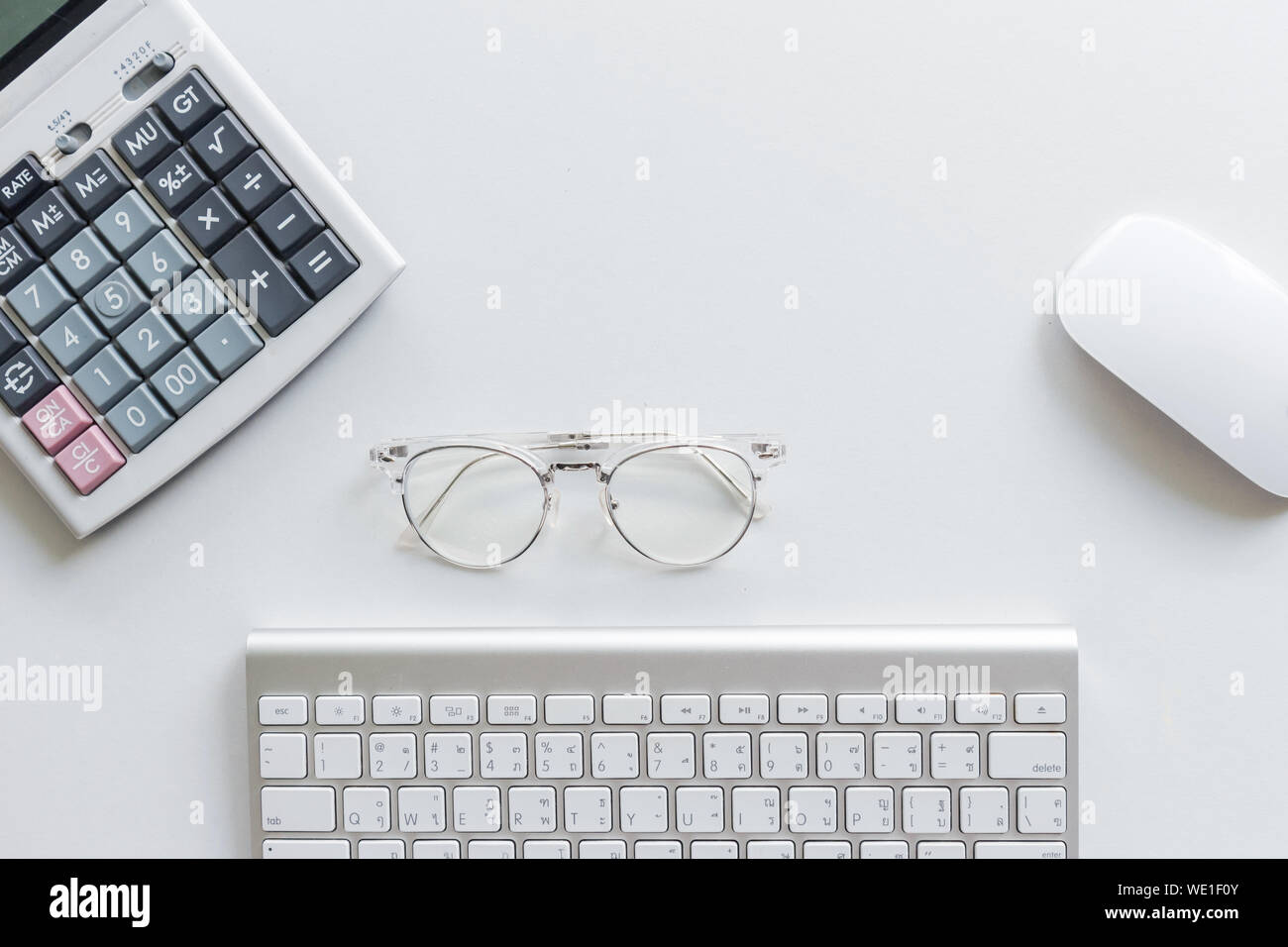 Elevato angolo di visione della calcolatrice da occhiali con tastiera e mouse su sfondo bianco Foto Stock