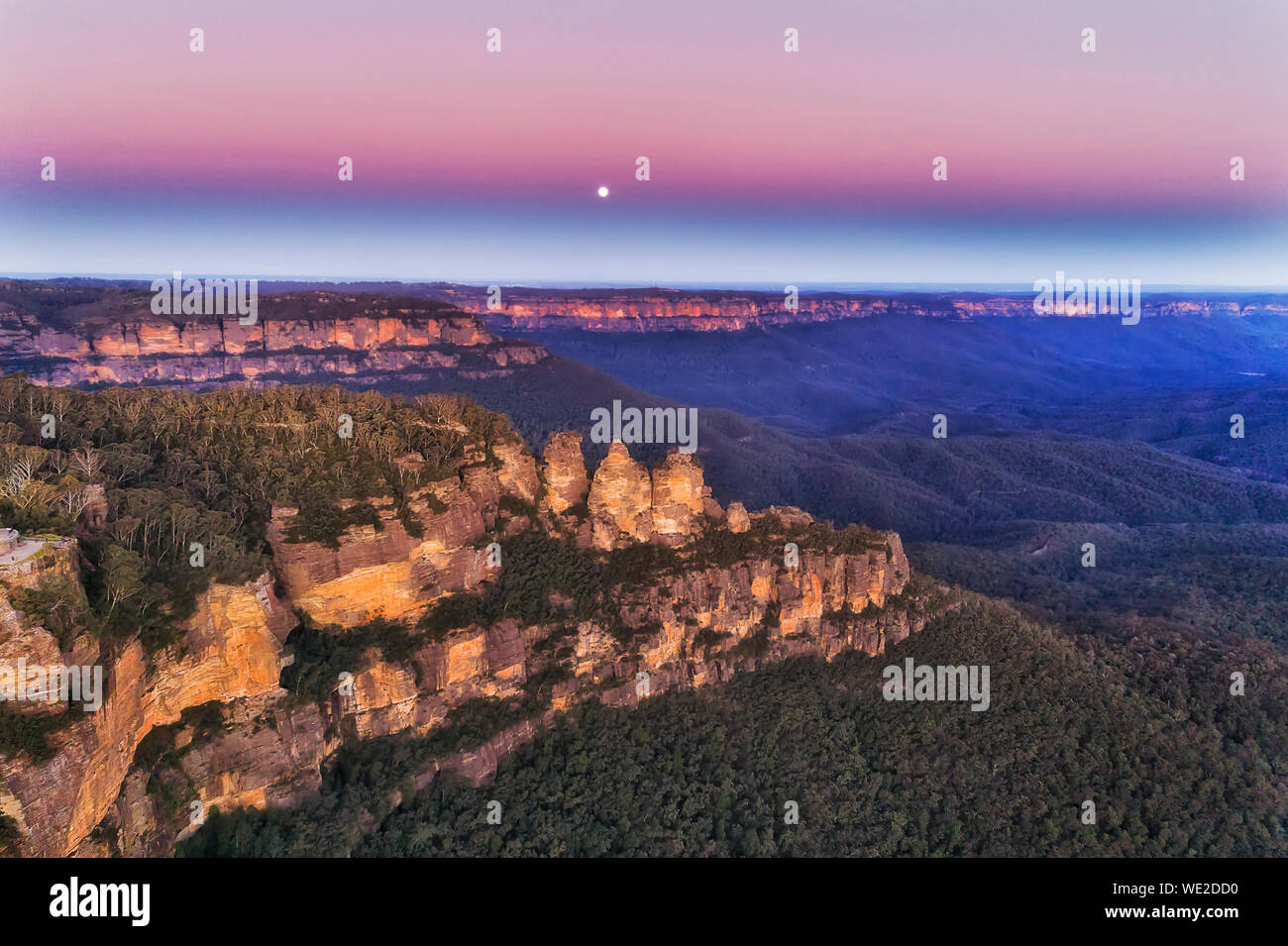 Rosa luminoso cielo e luna sulla formazione rocciosa Tre Sorelle nelle Blue Mountains in Australia al tramonto - una elevata vista aerea lungo scogliere di arenaria Foto Stock