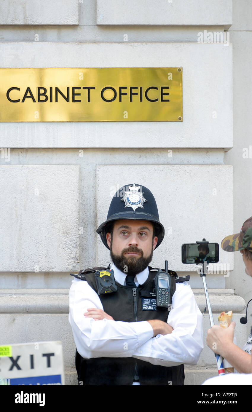 Londra, Inghilterra, Regno Unito. Pollice officer filmata su un telefono cellulare alla porta del Cabinet Office in Whitehall Foto Stock