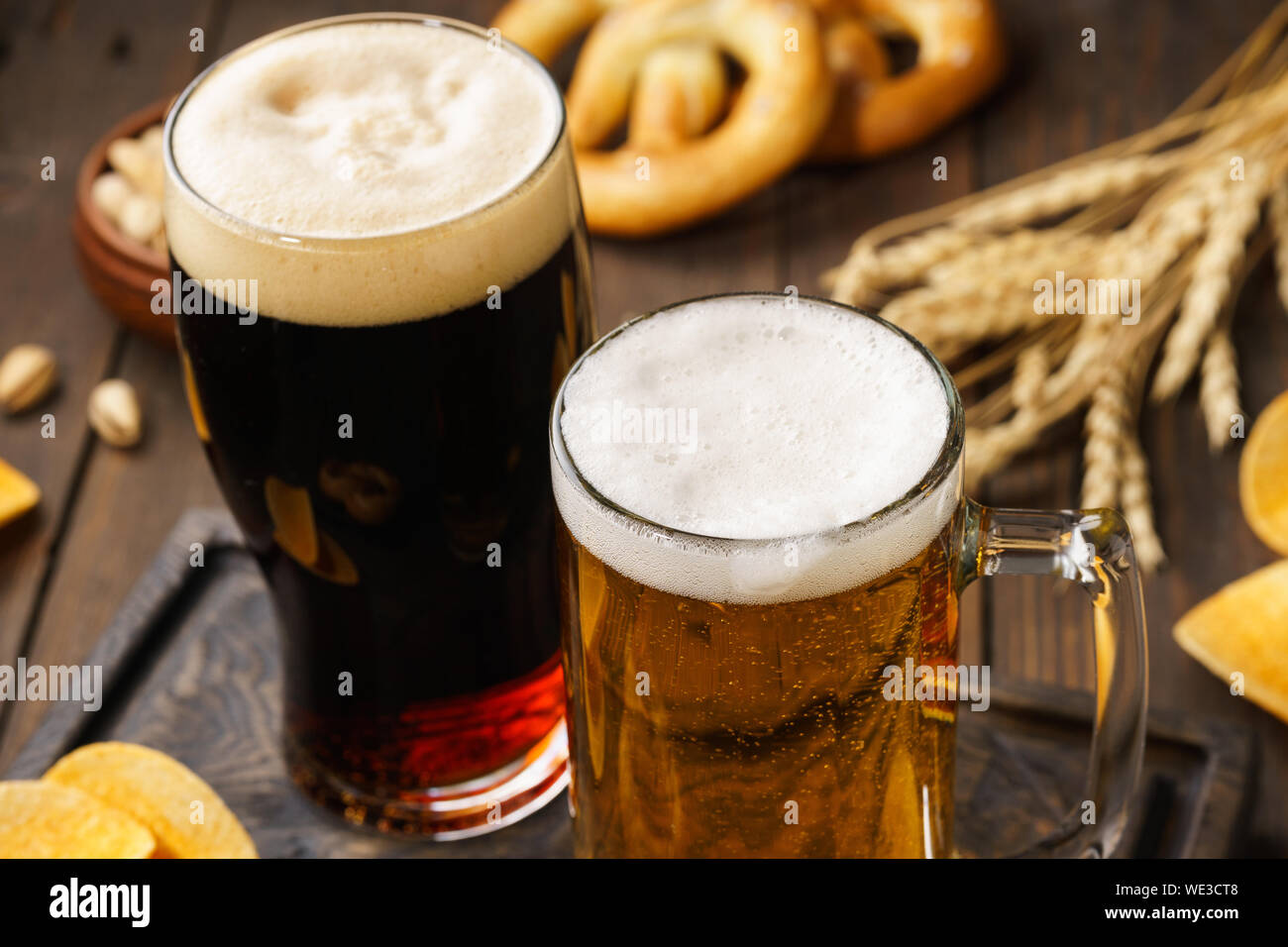 Due bicchieri di birra - luce e buio con vari snack in background. Close-up shot. Foto Stock