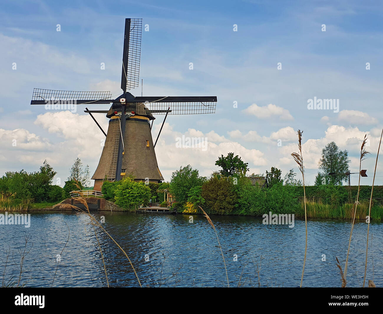 Vecchio mulino nei pressi di un canale per acqua a Kinderdijk Overwaard nei Paesi Bassi. Il mulino a vento di Patrimonio Mondiale Unesco con unica vista olandese come meta turistica molto attr Foto Stock