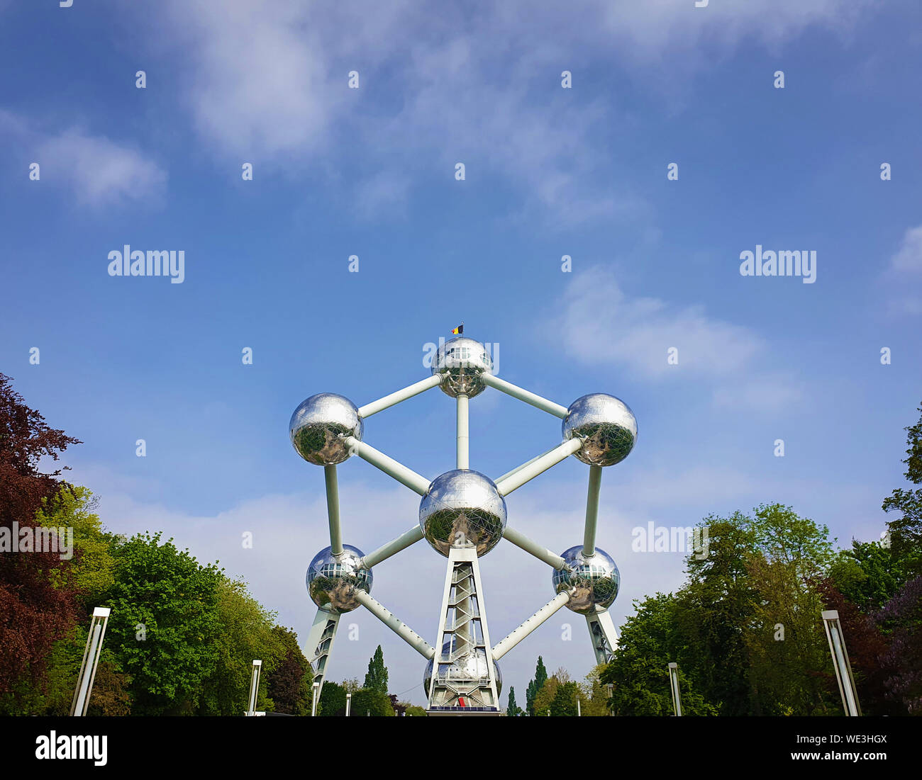 Famoso Atomium landmark tra alberi alley su un cielo blu sullo sfondo di Bruxelles in Belgio. Foto Stock