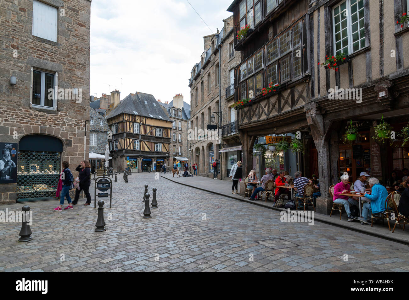 Dinan, Brittany, Francia - 20 Giugno 2019: acciottolata strada storica Place des Merciers a Dinan con persone a pranzare in ristoranti in un giorno di estate Foto Stock