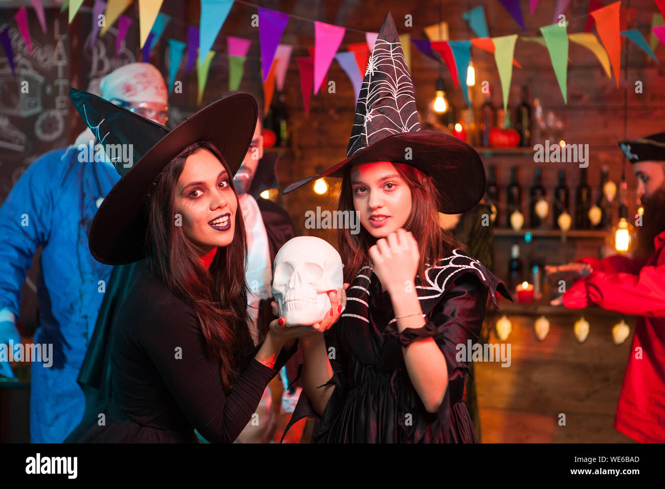 Giovane e bella streghe con grandi cappelli celebrare Halloween. Scary medico in background. Foto Stock