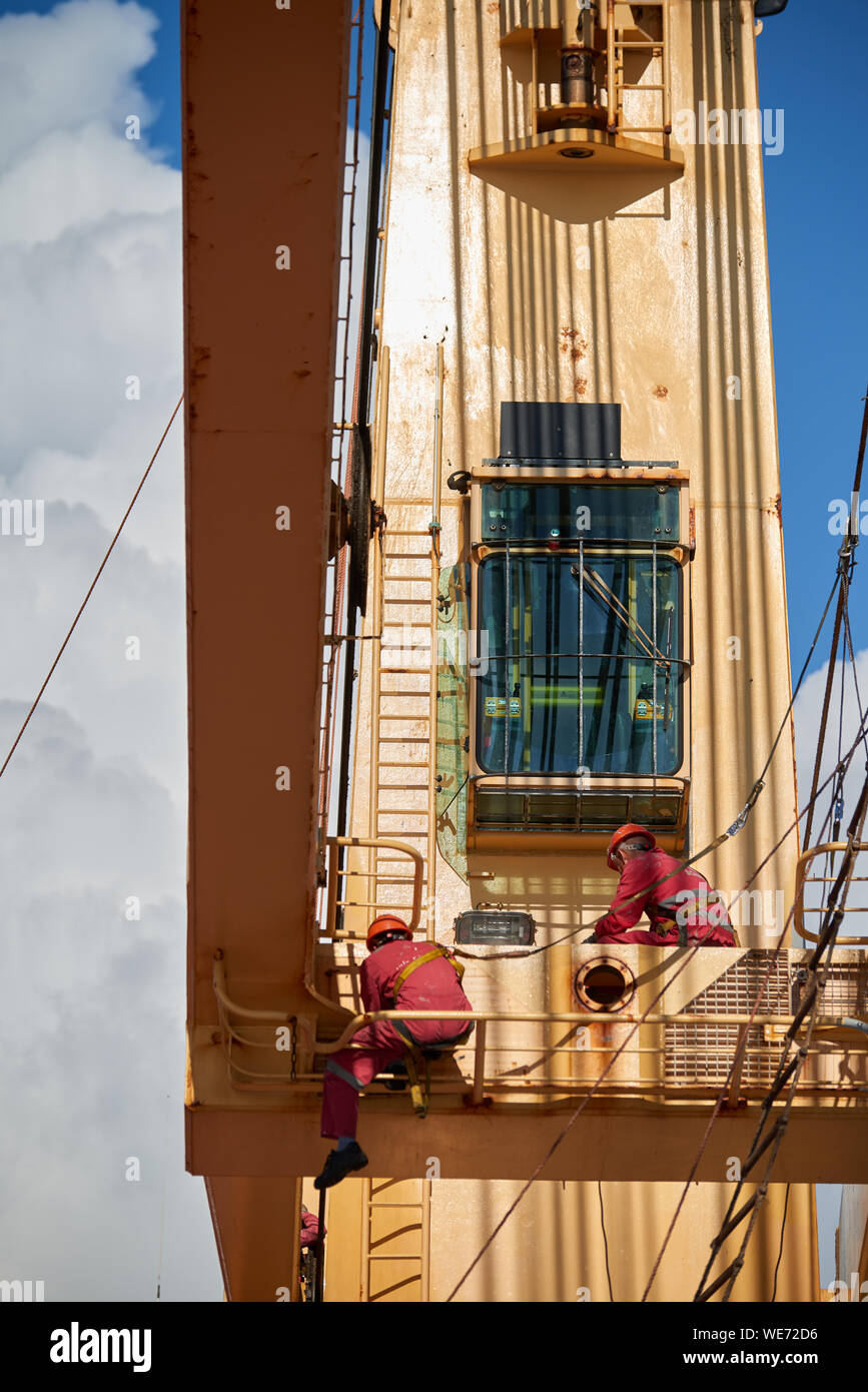 Oceano atlantico, il mare aperto - Circa nel marzo 2019: International Equipaggio delle navi di eseguire la lavorazione aloft, pittura di gru a bordo di un mercantile internazionale sh Foto Stock