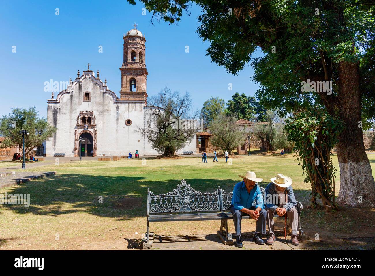 Messico, Michoacan stato, Tzintzuntzan, messicano due su di un banco prima della chiesa Foto Stock