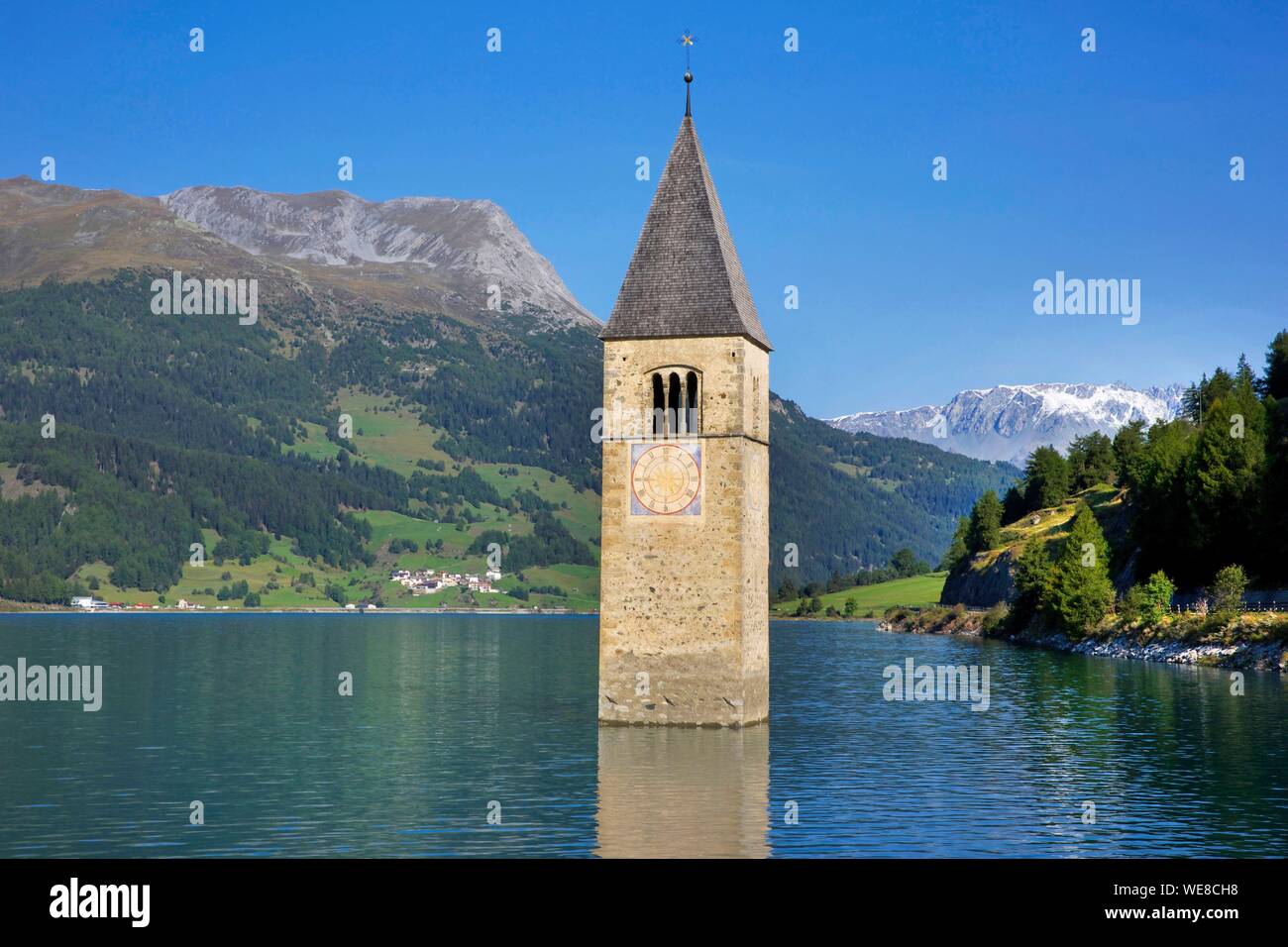 L'Italia, provincia autonoma di Bolzano, Lago di Resia, travolto campanile emergenti dalle acque del lago circondato da lussureggianti montagne Foto Stock