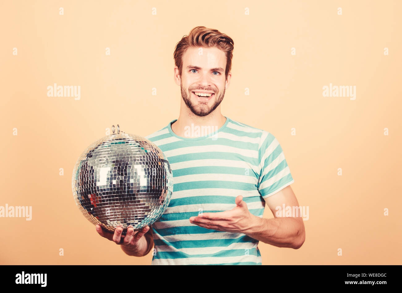 Allegro dj uomo. Uomo bello tenere palla da discoteca. Danze da discoteca night club. Musica retrò. Ragazzo che vi invitano a parte. Migliaia di minuscoli specchi che riflettono la creazione delle luci di atmosfera da discoteca. Come circa la parte. Foto Stock