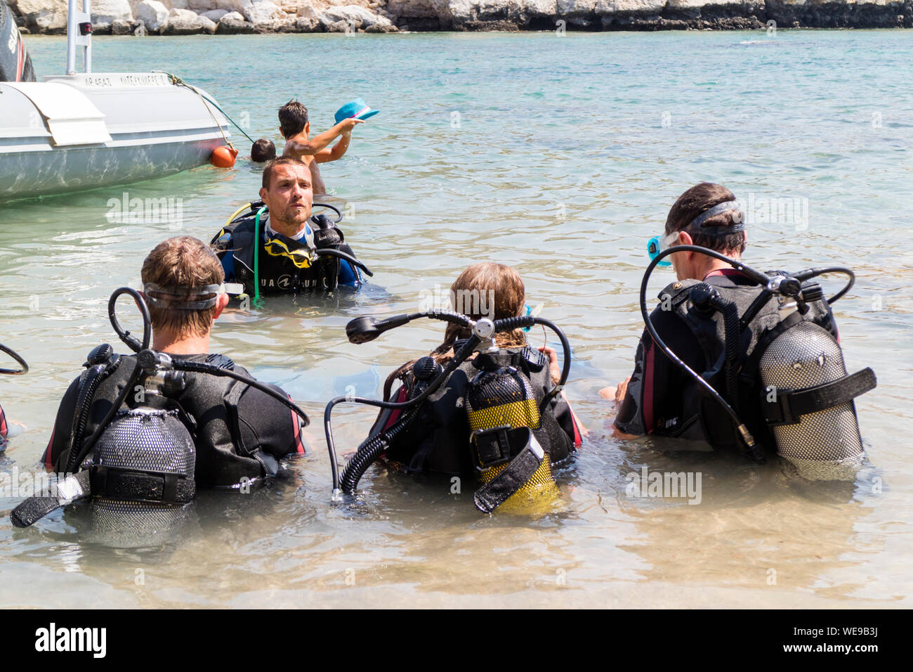 Un istruttore di immersioni parla di tre subacquei in mare Foto Stock