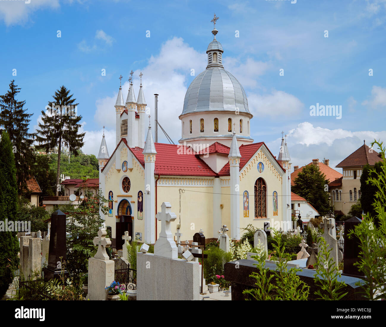 Chiesa Ortodossa Romena di San Paraskeva e circondante il cimitero con lapidi e croce in Brasov, Romania Foto Stock