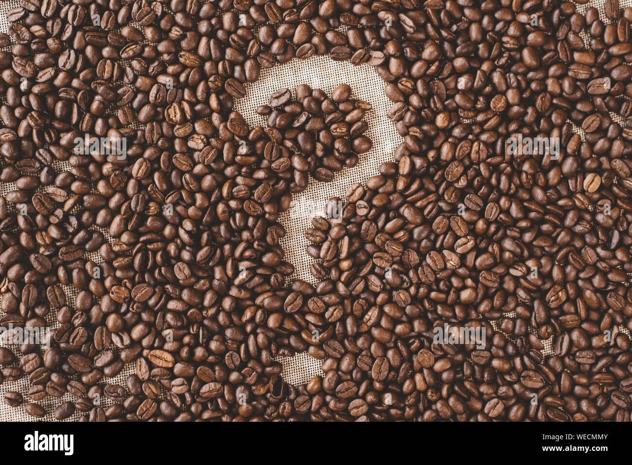 Punto interrogativo realizzato da un caffè in grani su un sacco di tela. concetto di quale tipo di caffè e domande Foto Stock