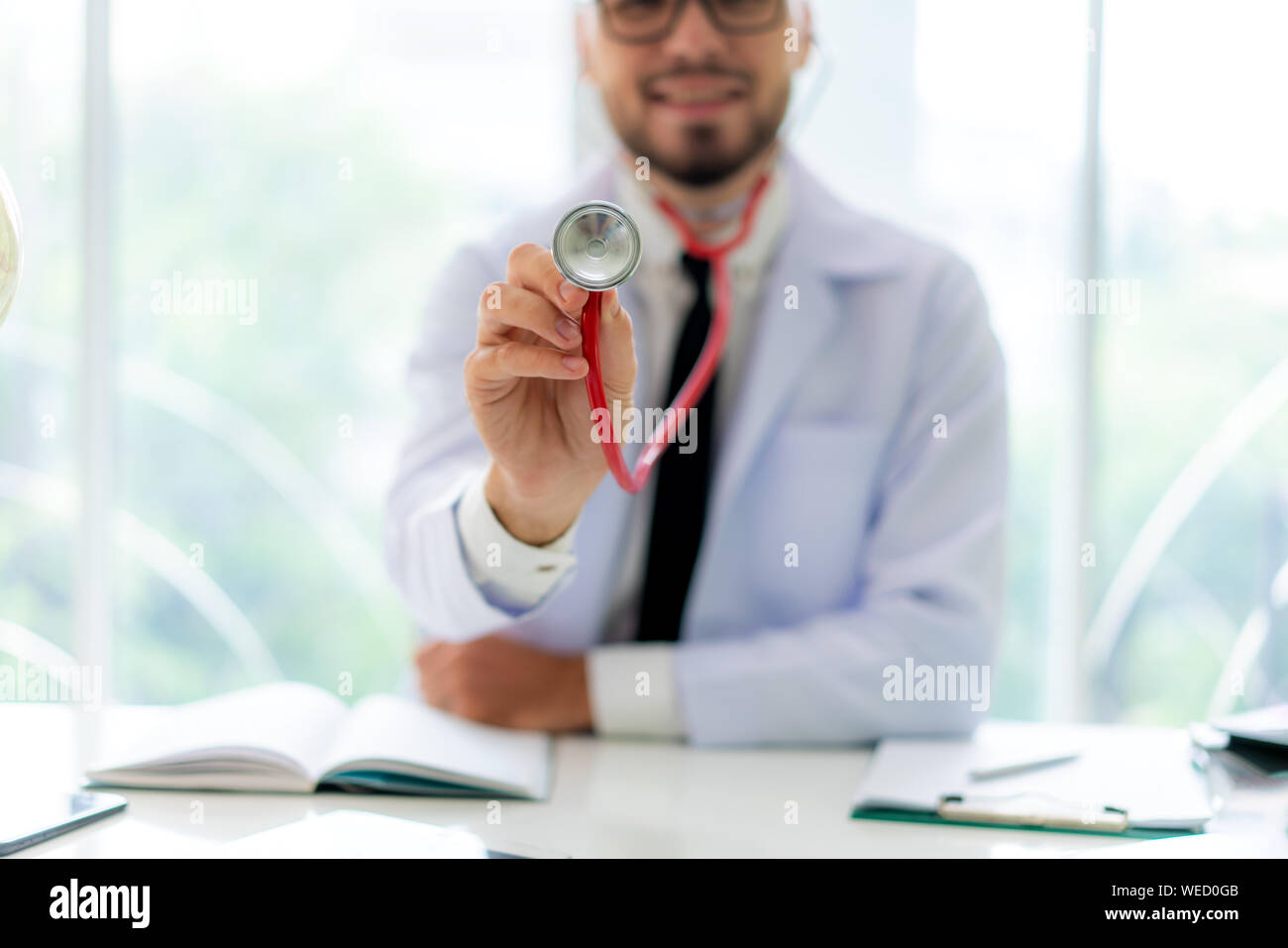 L'uomo medico con lo stetoscopio in mano. Egli sorride dolcemente per i pazienti che vengono diagnosticati. Foto Stock