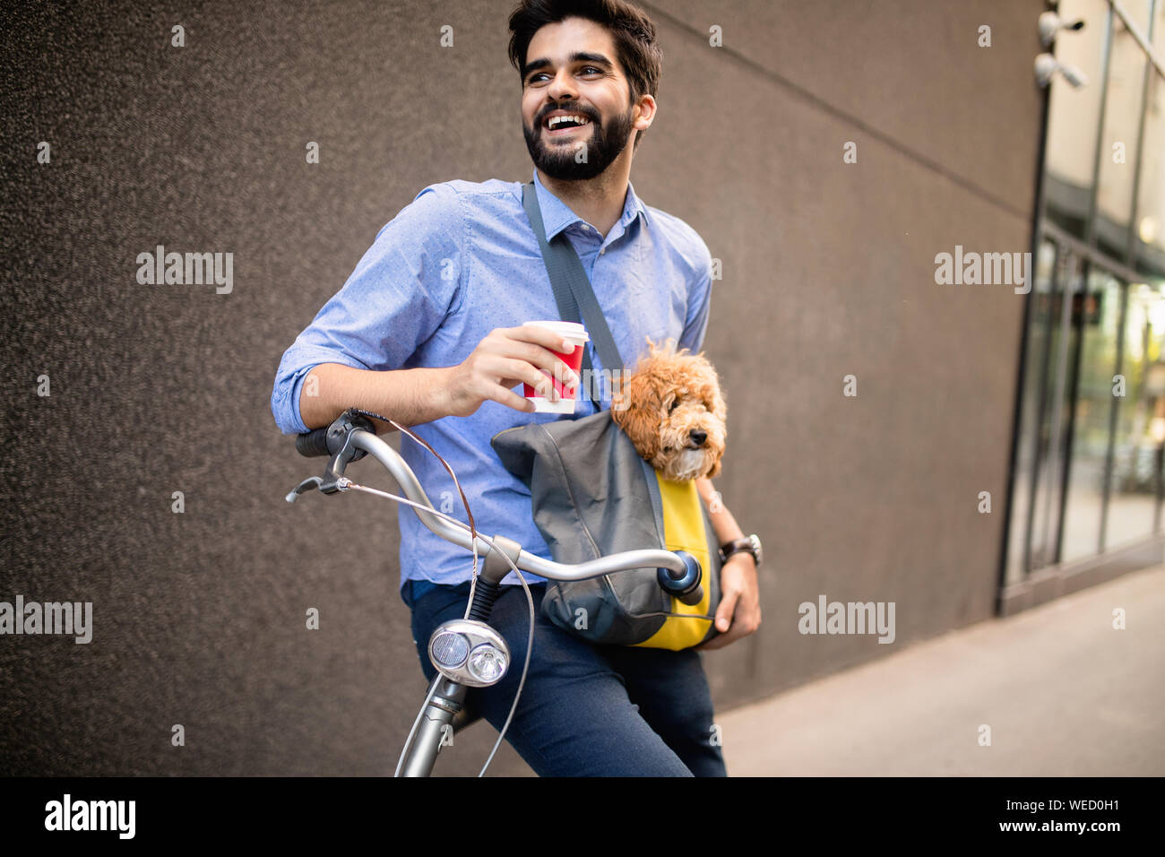 Giovane uomo di bere il caffè mentre è seduto sulla sua bicicletta con il cane all'aperto Foto Stock