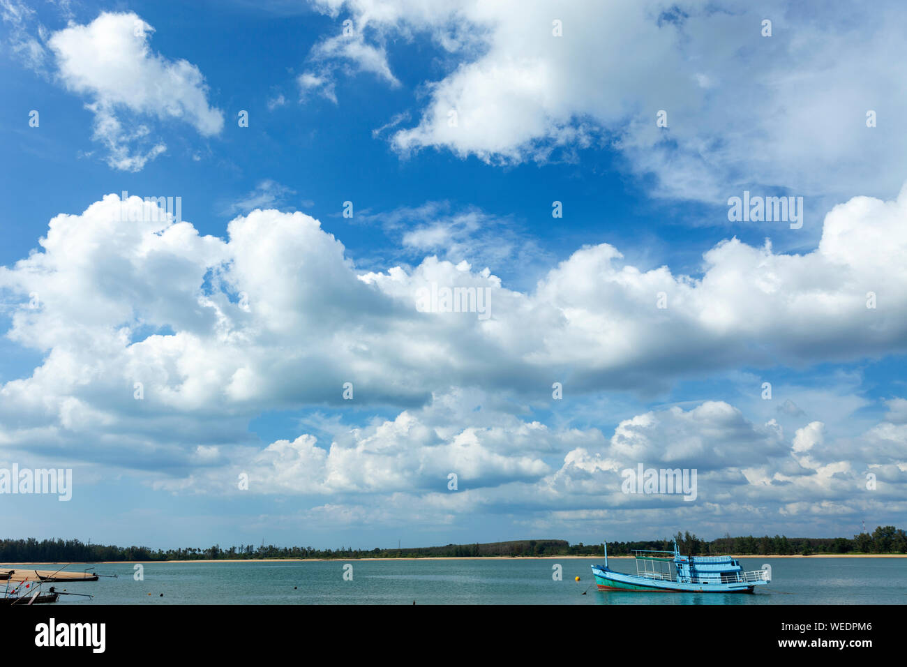 Bella giornata di sole con cielo blu, il bianco delle nuvole sopra il mare e la barca da pesca. Foto Stock