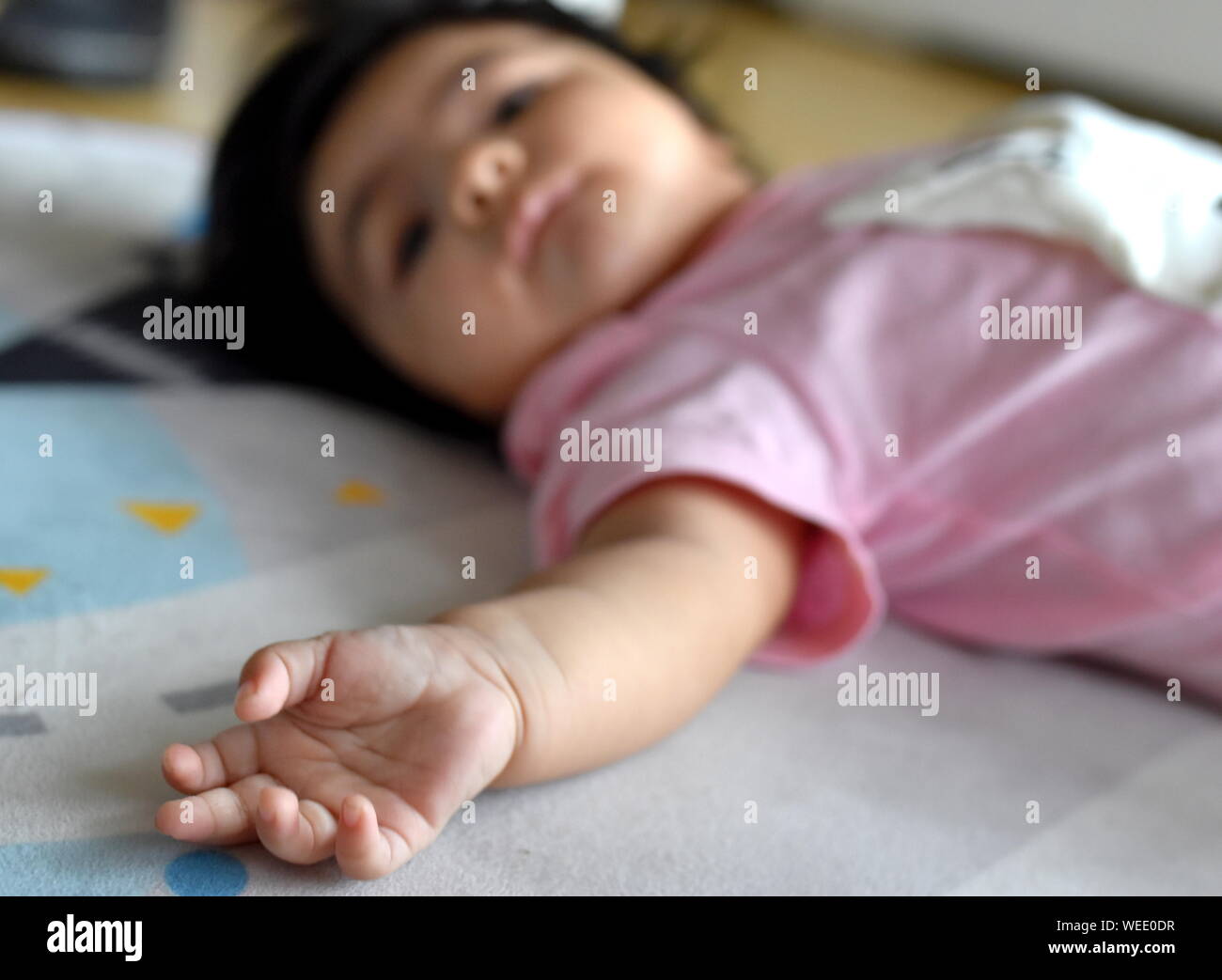 Le dita e la mano della bambina sdraiato in vivaio Foto Stock