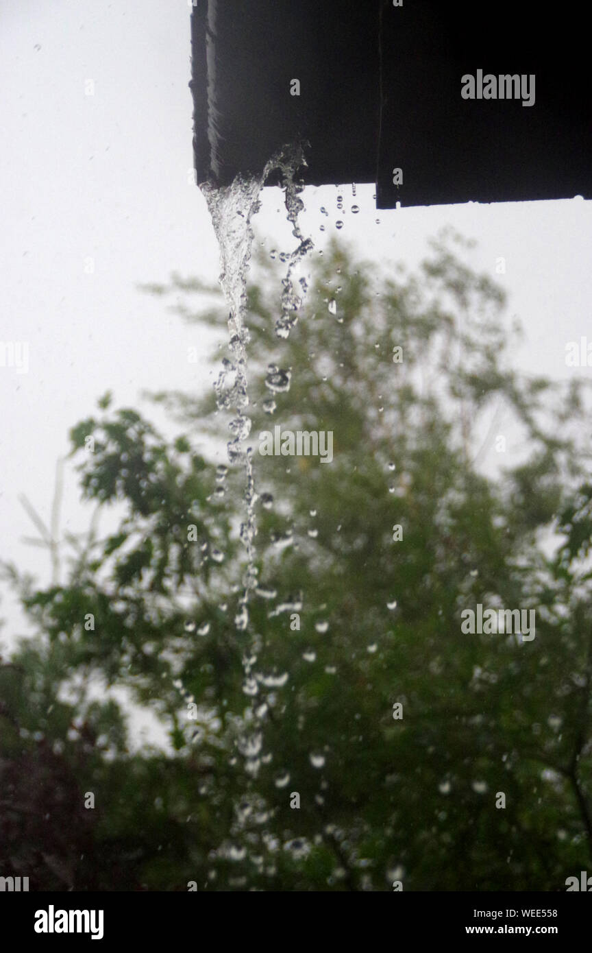 Flusso di acqua viene versata dalla grondaia. Home in pioggia intensivo. Foto Stock