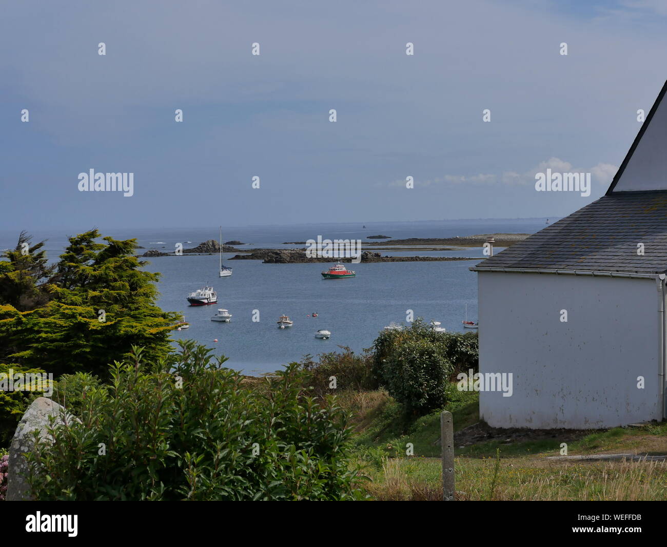 L'île de molène et son merveilleux port et ses bateaux multicolori et ses quais en granit et onu banc bleu et blanc et l'île prise depuis le grandi Foto Stock