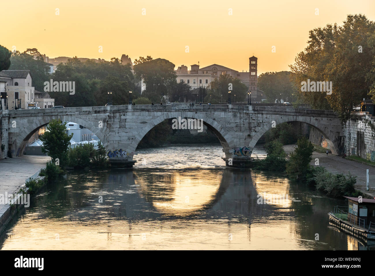 Sunrise oltre il Fiume Tevere e il Ponte Cestio con il campanile di Santa Maria in Cosmedin in distanza, centrali di Roma, Italia. Foto Stock