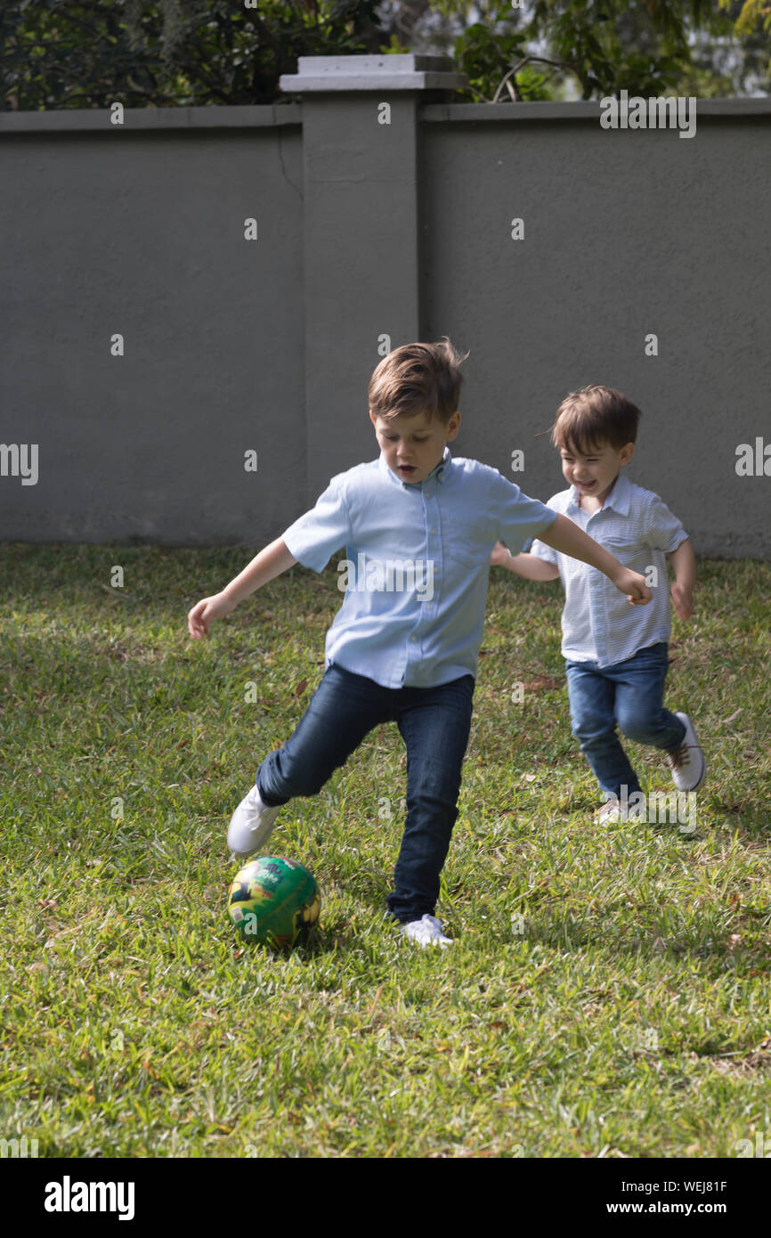 3 e 5 anno vecchio fratelli che giocano a calcio nel loro back yard, Clearwater, Florida Foto Stock