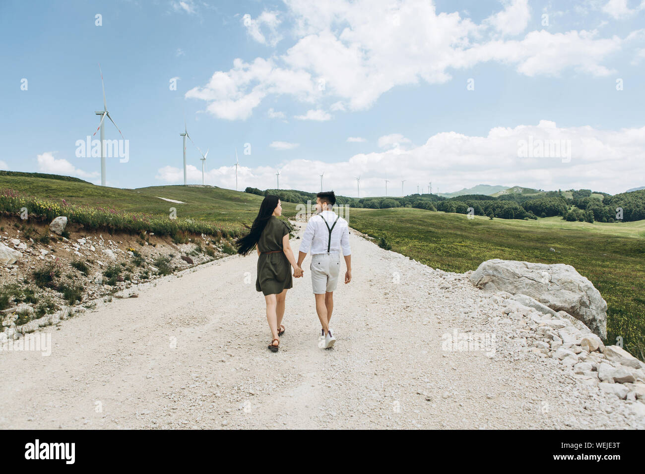 Una giovane coppia tiene per mano e camminare insieme lungo la strada. Foto Stock