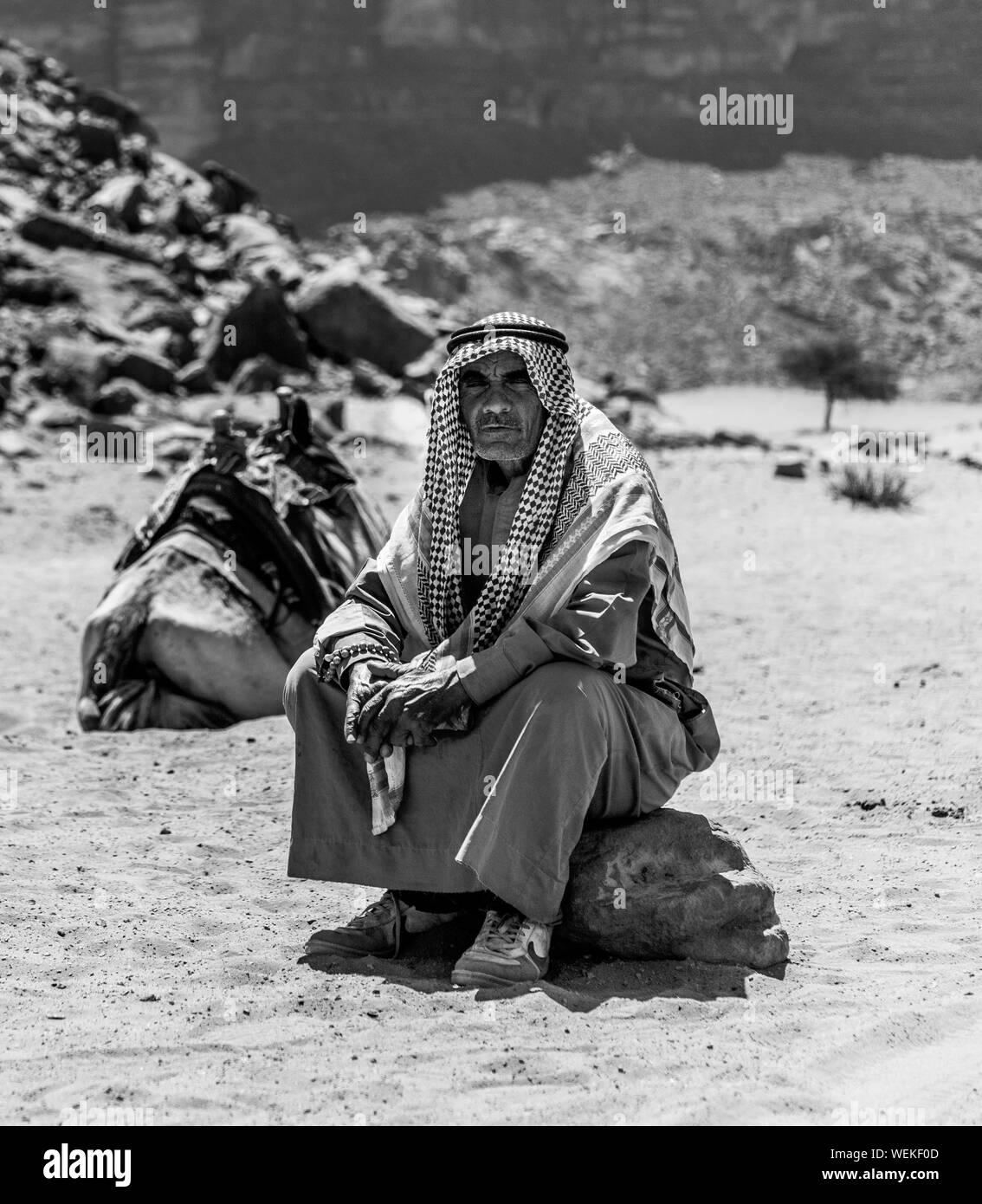 Una foto in bianco e nero di un beduino seduto su una roccia (Wadi Rum). Foto Stock