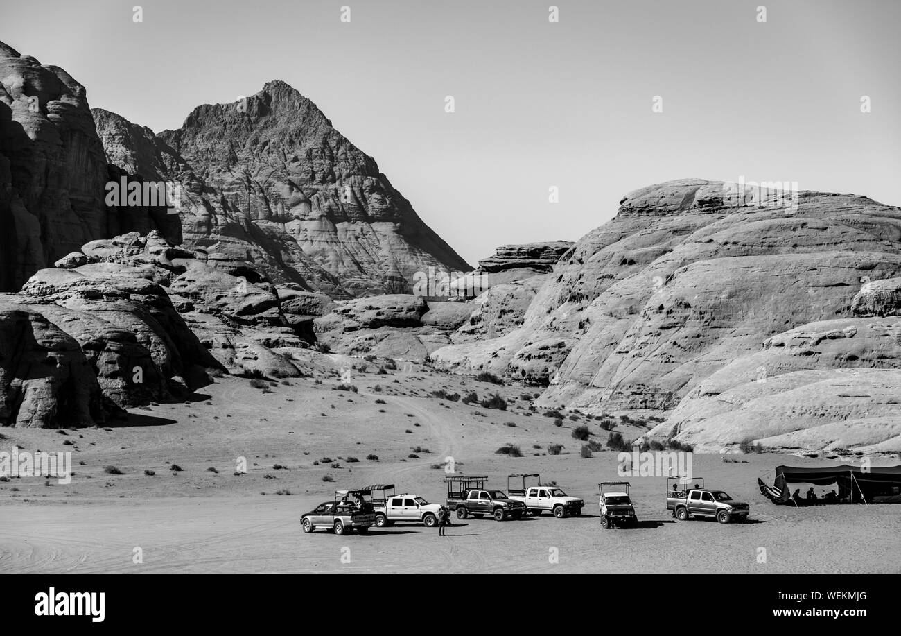 Una foto in bianco e nero di molti jeep accanto a Wadi Rum il paesaggio. Foto Stock