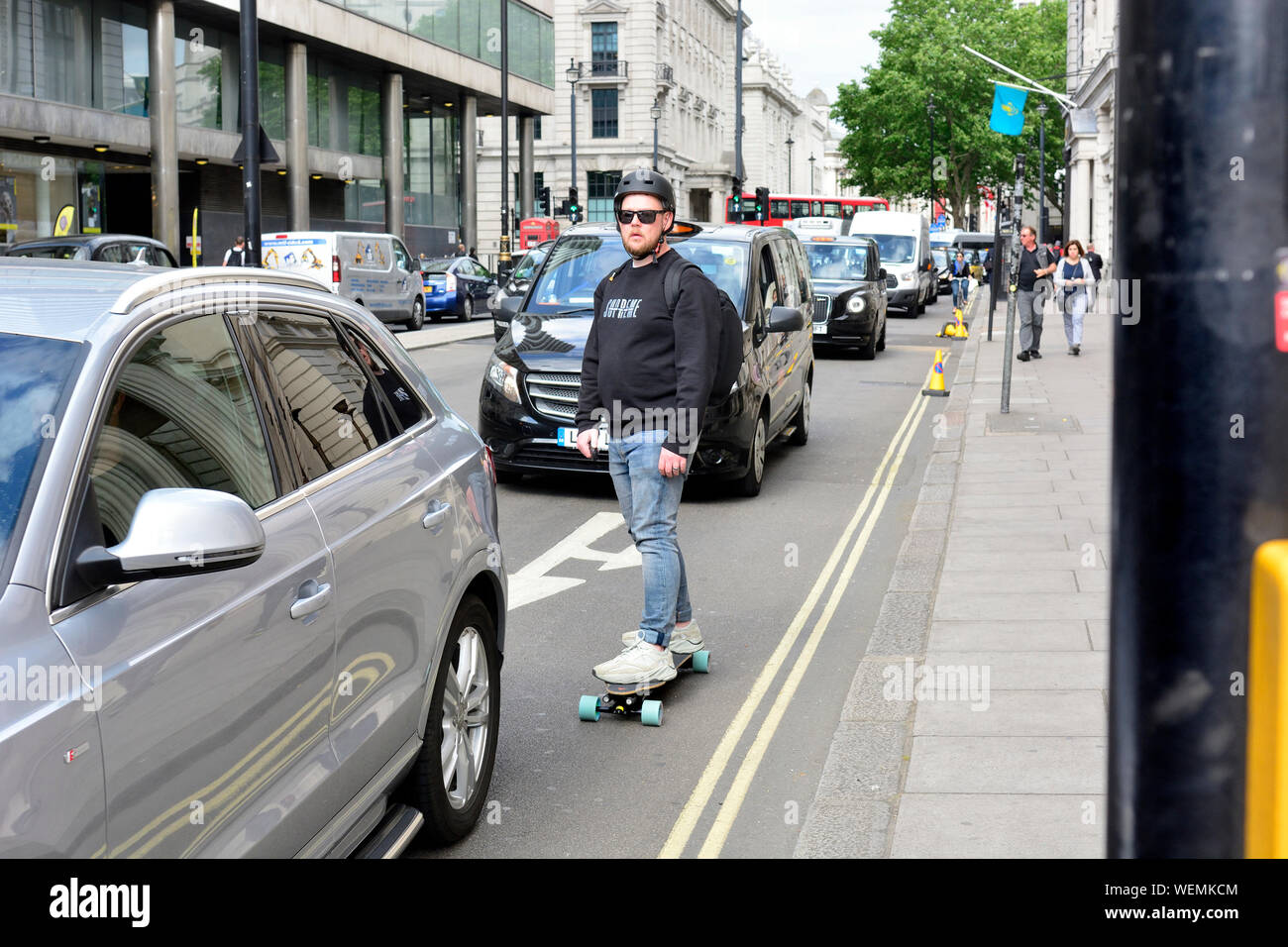 Londra, Inghilterra, Regno Unito. L'uomo su uno skateboard nel traffico Foto Stock