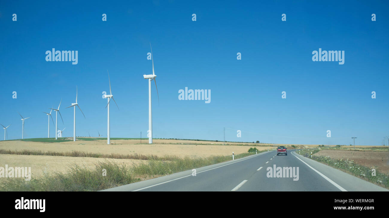 Il viaggio in auto attraverso pascoli lungo con turbine eoliche. Spagna del sud Foto Stock