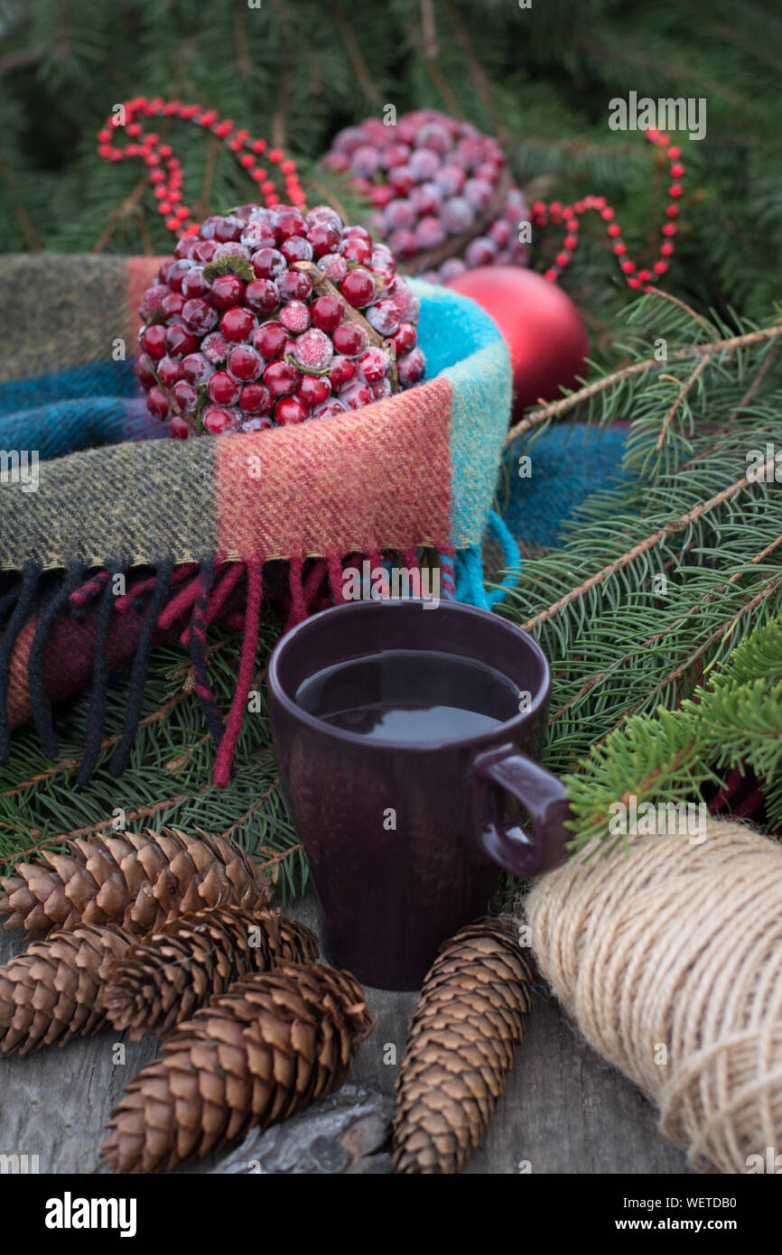 Rientrano ancora in vita con tazza di tè caldo su tavola in legno rustico. Il decor di coni, calde coperte, Abete rami. Il tempo di Natale. Foto Stock