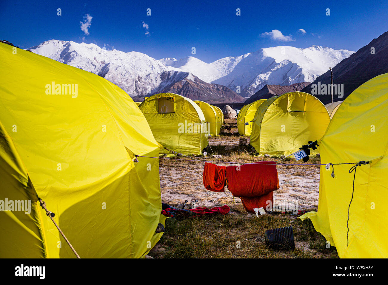 BaseCamp a Peak Lenin, Kirghizistan. 48 tende gialle possono ospitare circa 100 ospiti nei mesi di luglio e agosto. Durante il resto dell'anno, la valle collinare, situata ad un'altitudine di 3.600 metri, non è più accessibile con i bus navetta che portano qui il campo base direttamente dall'aeroporto di OSH, a 330 km di distanza, in estate Foto Stock
