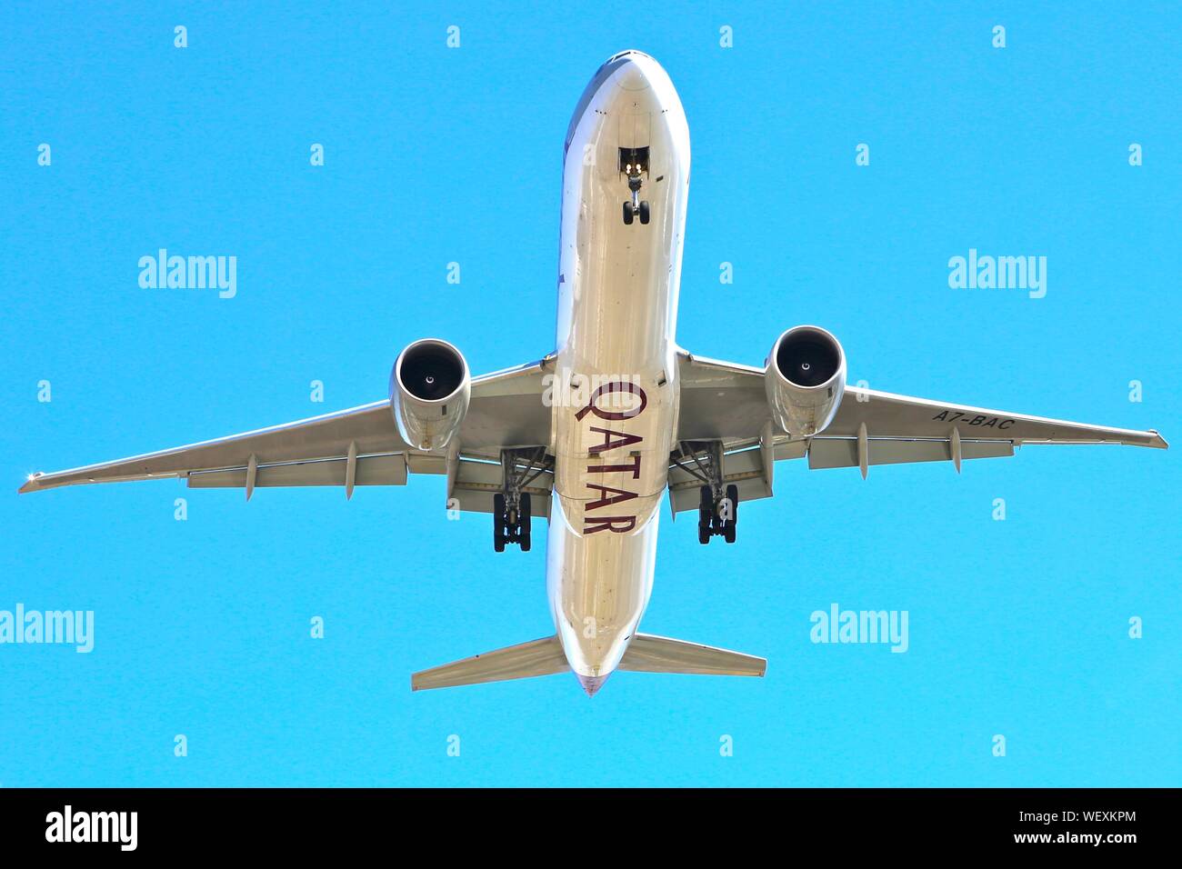 La Qatar Airways Boeing 777 sull approccio finale a New York con ruote verso il basso e cielo blu dietro Foto Stock