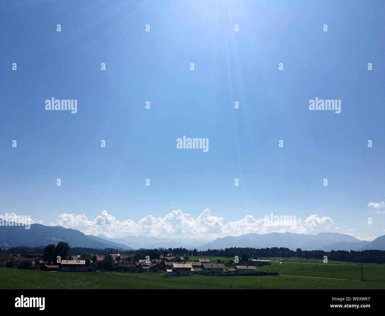 Case sul campo erboso contro il cielo blu durante la giornata di sole Foto Stock