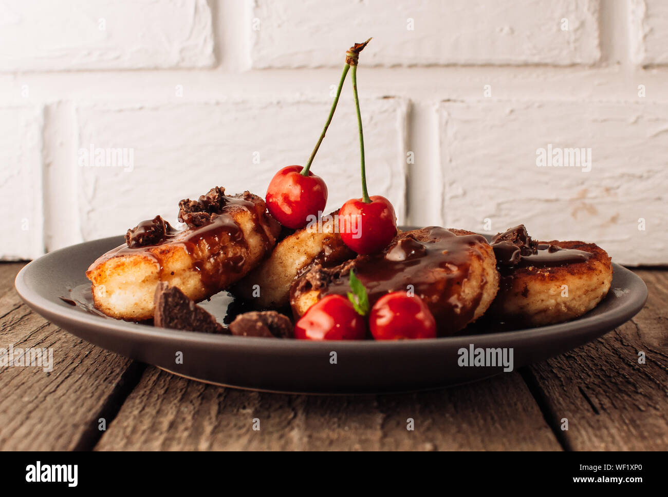 Il cibo della colazione gustosa concetto. La cheesecake, cheesecake, cagliata frittelle con ciliegie e cioccolato su uno sfondo nero da una tabella di cemento e un wh Foto Stock