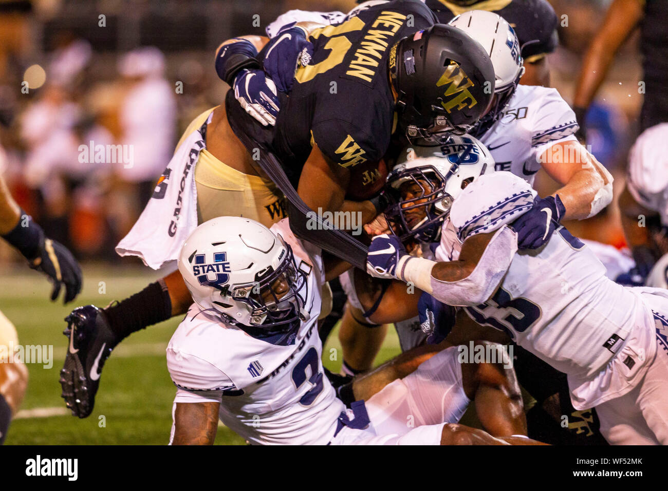 Agosto 30, 2019: Wake Forest Demon diaconi quarterback Jamie Newman (12) viene arrestato da Utah State Aggies linebacker Kevin Meitzenheimer (33) nel NCAA matchup a BB&T Campo in Winston-Salem, NC. (Scott Kinser/Cal Sport Media) Foto Stock