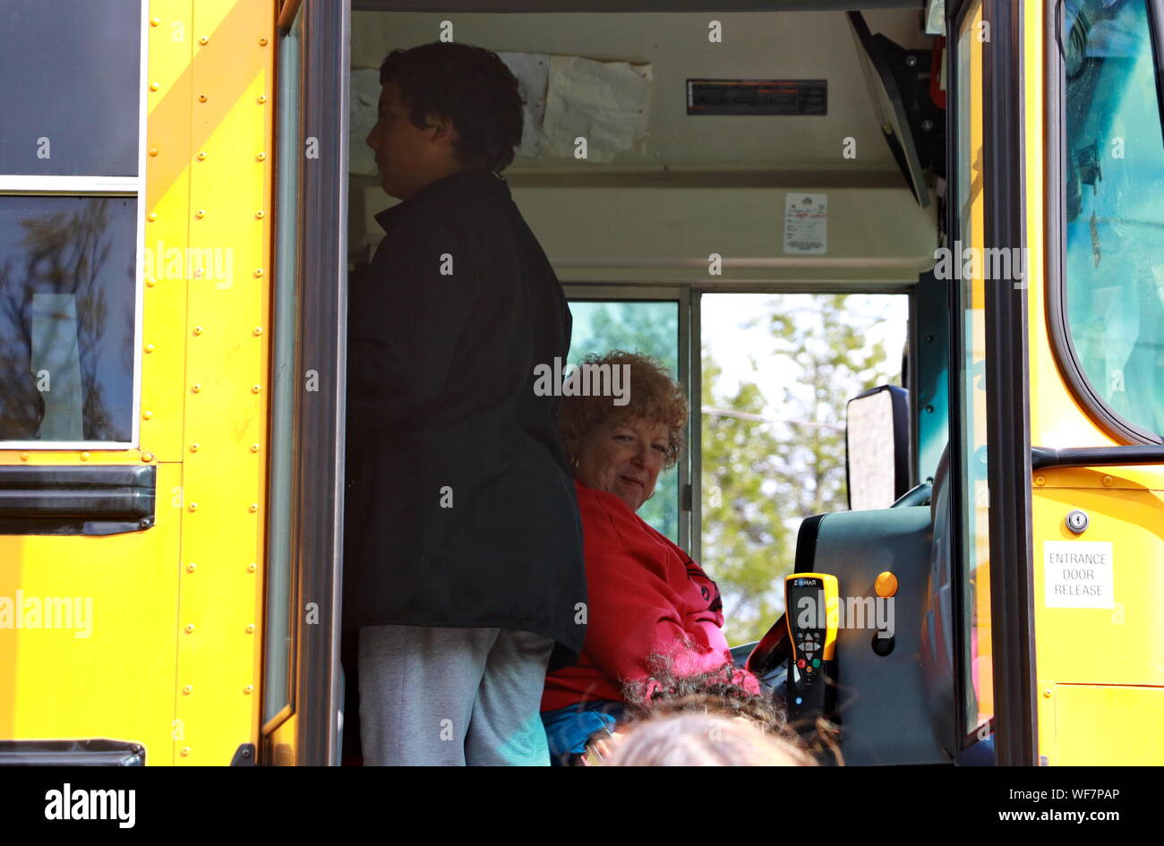 Meriden, CT / STATI UNITI D'America - 27 Aprile 2019: femmina caucasica di mezza età conducente di bus di prelevare i bambini e gli altri passeggeri Foto Stock