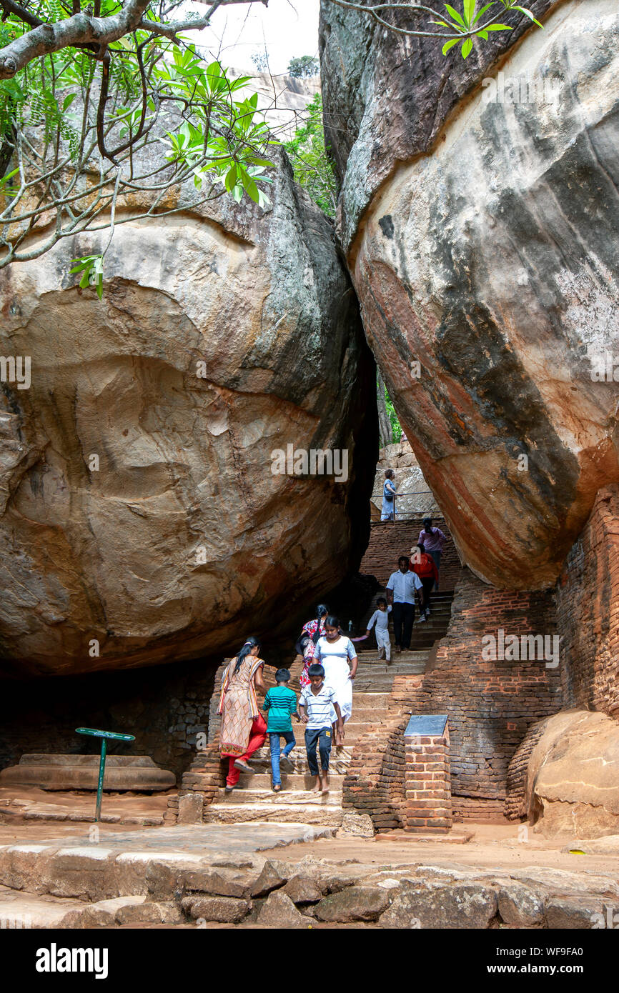 I visitatori di Sigiriya rock in Sri Lanka passano attraverso Boulder Arch numero uno. Questo formato parte dell'antico percorso al vertice di rocce. Foto Stock