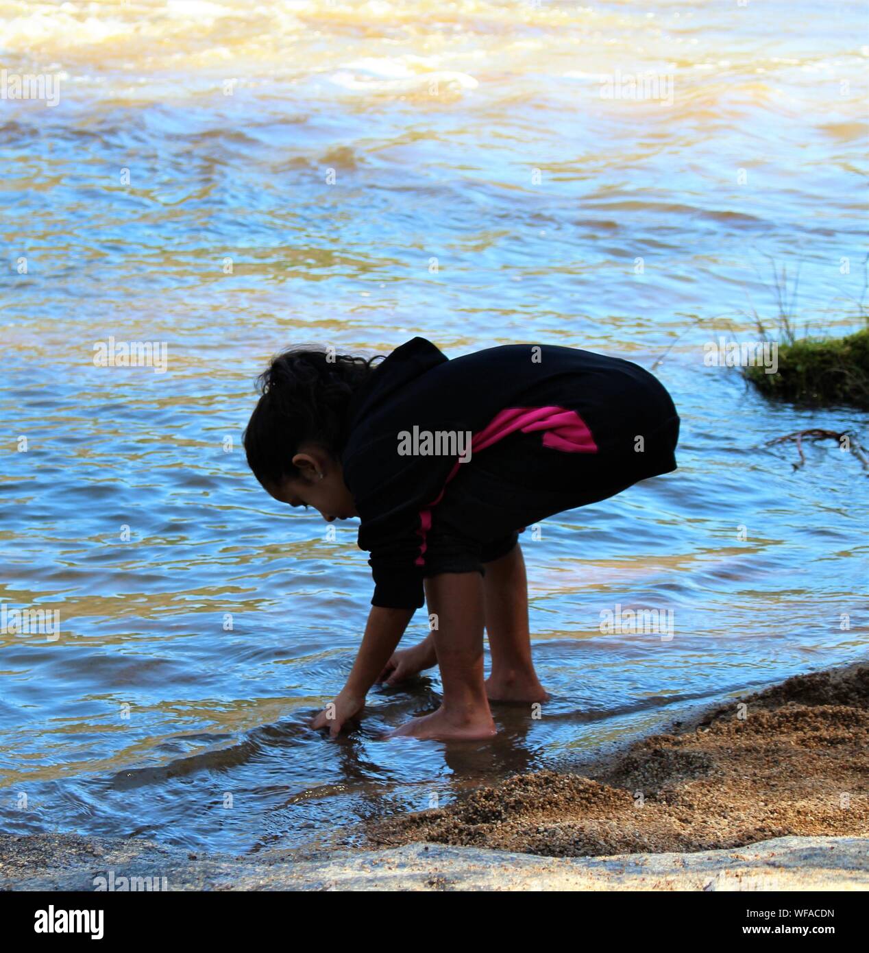 Bambina alla ricerca di qualcosa sulla riva del mare Foto Stock