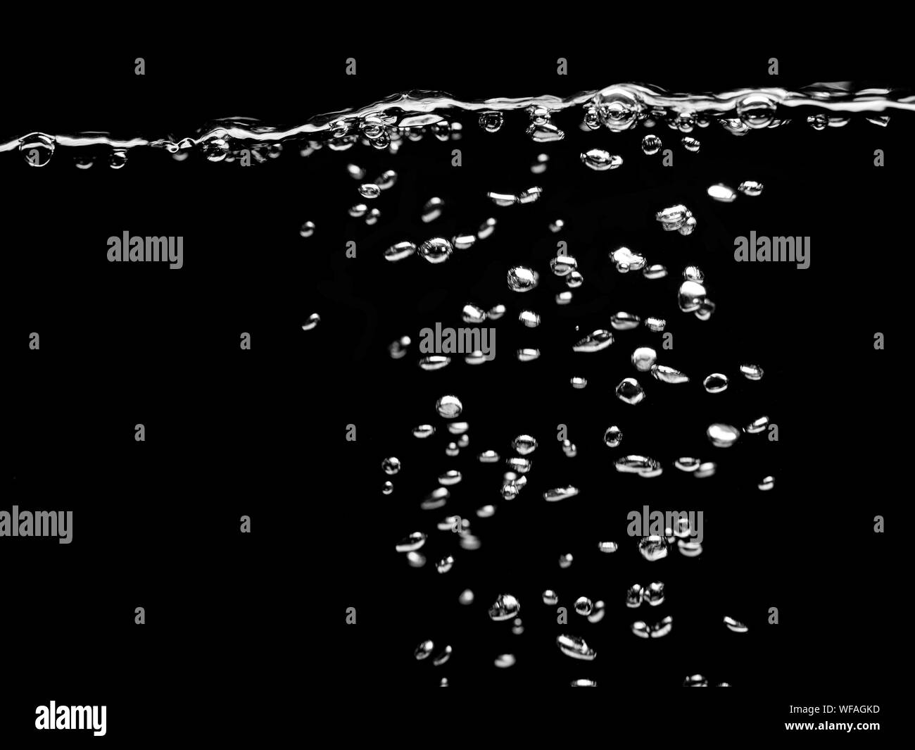 Gocce d'acqua bolle su uno sfondo scuro, bollicine nell'acqua, bevanda effervescente Foto Stock