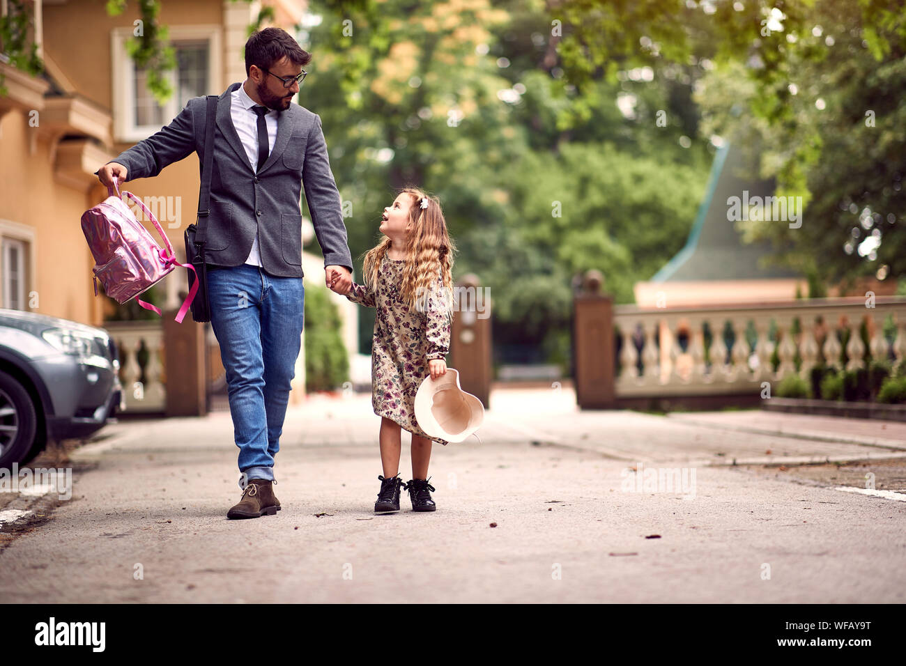 Padre e figlio piccolo tenendo le mani andando a scuola Foto Stock