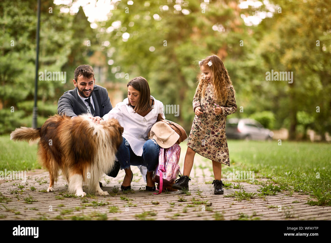 La famiglia felice si diverte con un cane nel parco. Foto Stock
