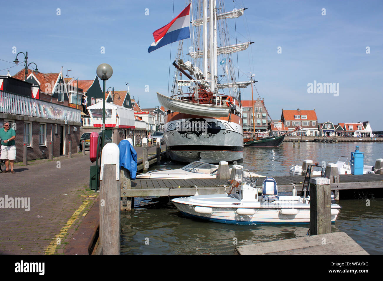 Una strada residenziale a Volendam dove vedrete tradizionali edifici in legno su un lato e il lavoro di pescherecci da traino e i pescherecci sull'altro lato. Foto Stock