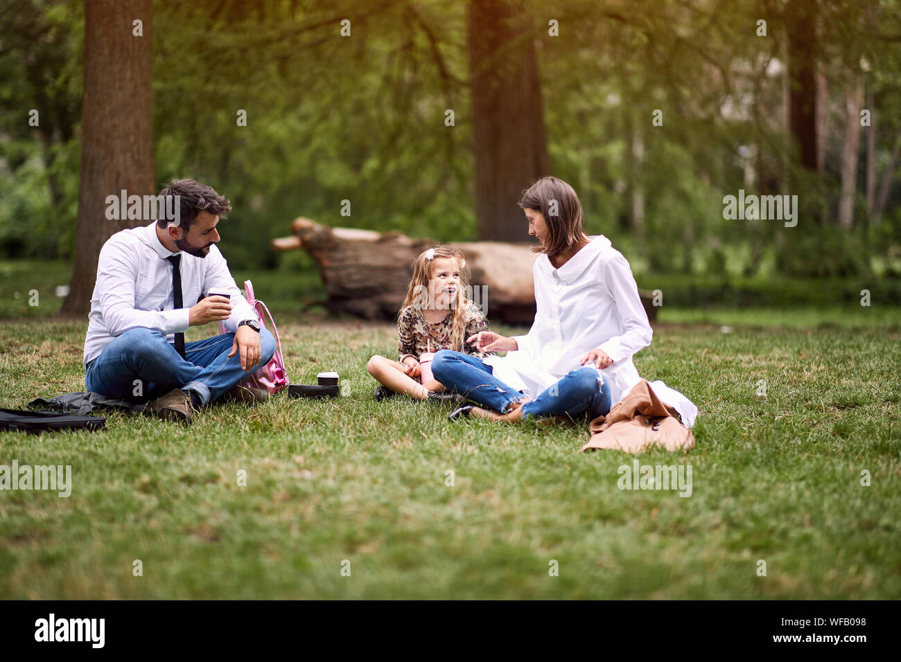 La famiglia felice dopo il lavoro e la scuola seduto e appoggiato al parco. Foto Stock