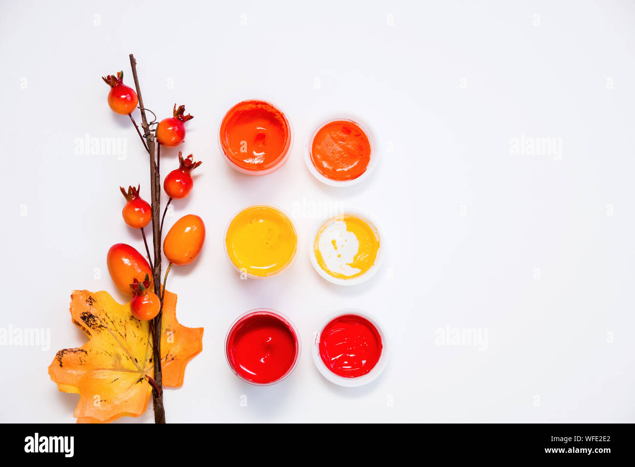 Colori luminosi di autunno, aprire vernici acriliche e un ramoscello decorativo con frutti di bosco e una foglia su sfondo bianco, close-up, copia dello spazio, laici piana. Foto Stock