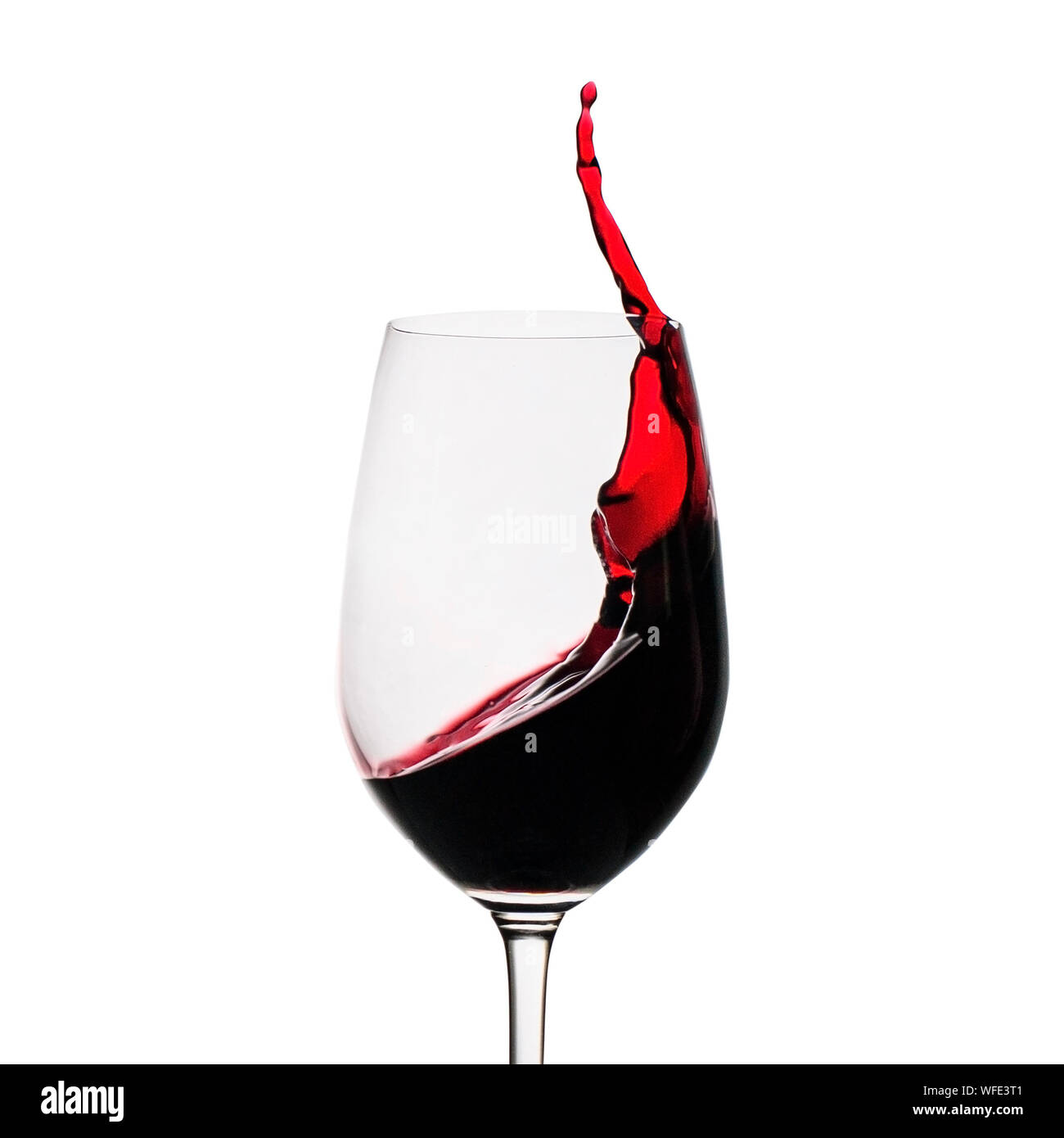 Congelare il movimento del vino rosso di schizzi fino al lato in un wineglass isolato su bianco con spazio di copia Foto Stock