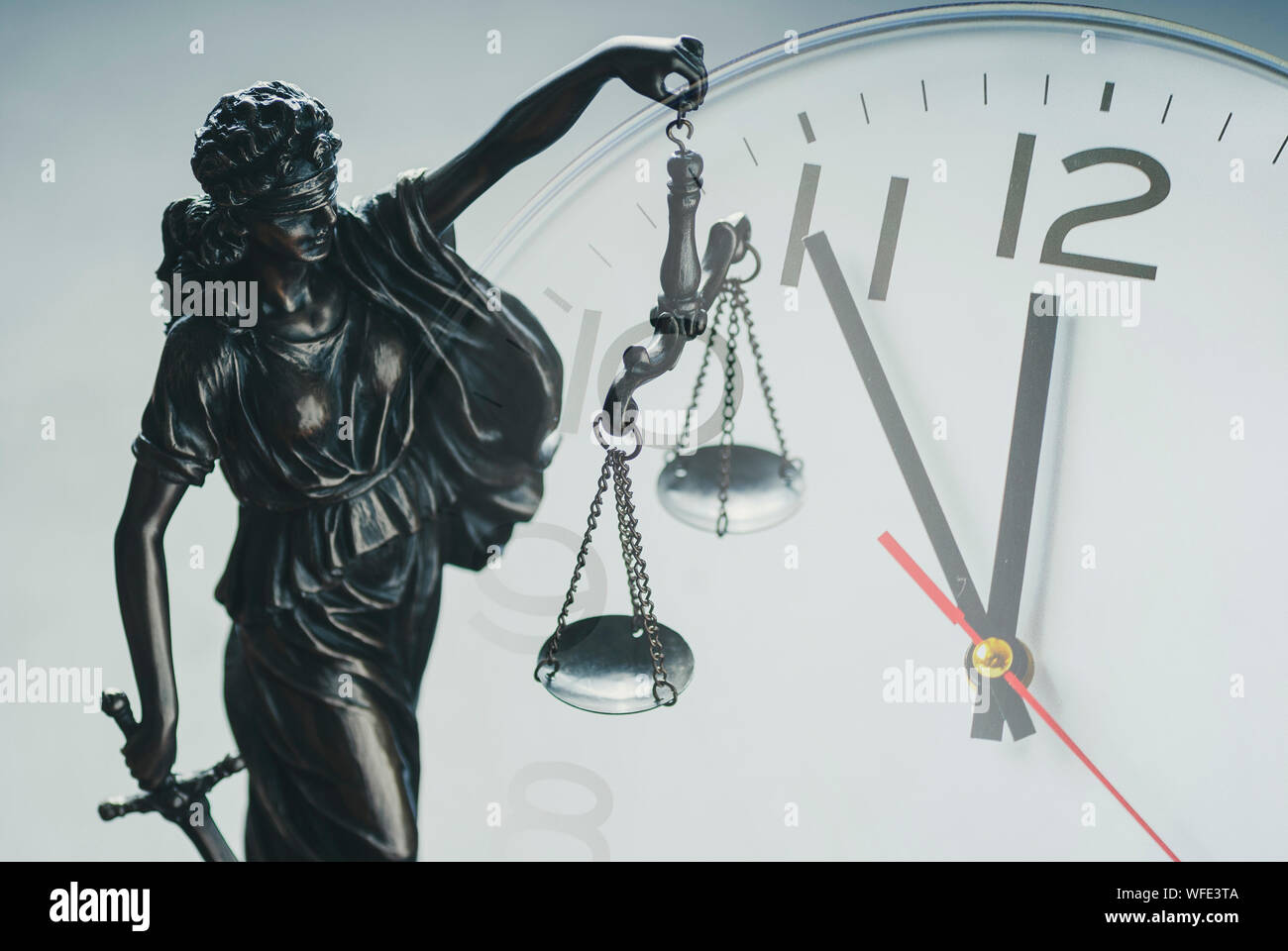 Statuetta di argento di giustizia tenendo la bilancia della giustizia e dell'applicazione della legge nella parte anteriore di un quadrante di orologio in una chiusura concettuale immagine composita Foto Stock