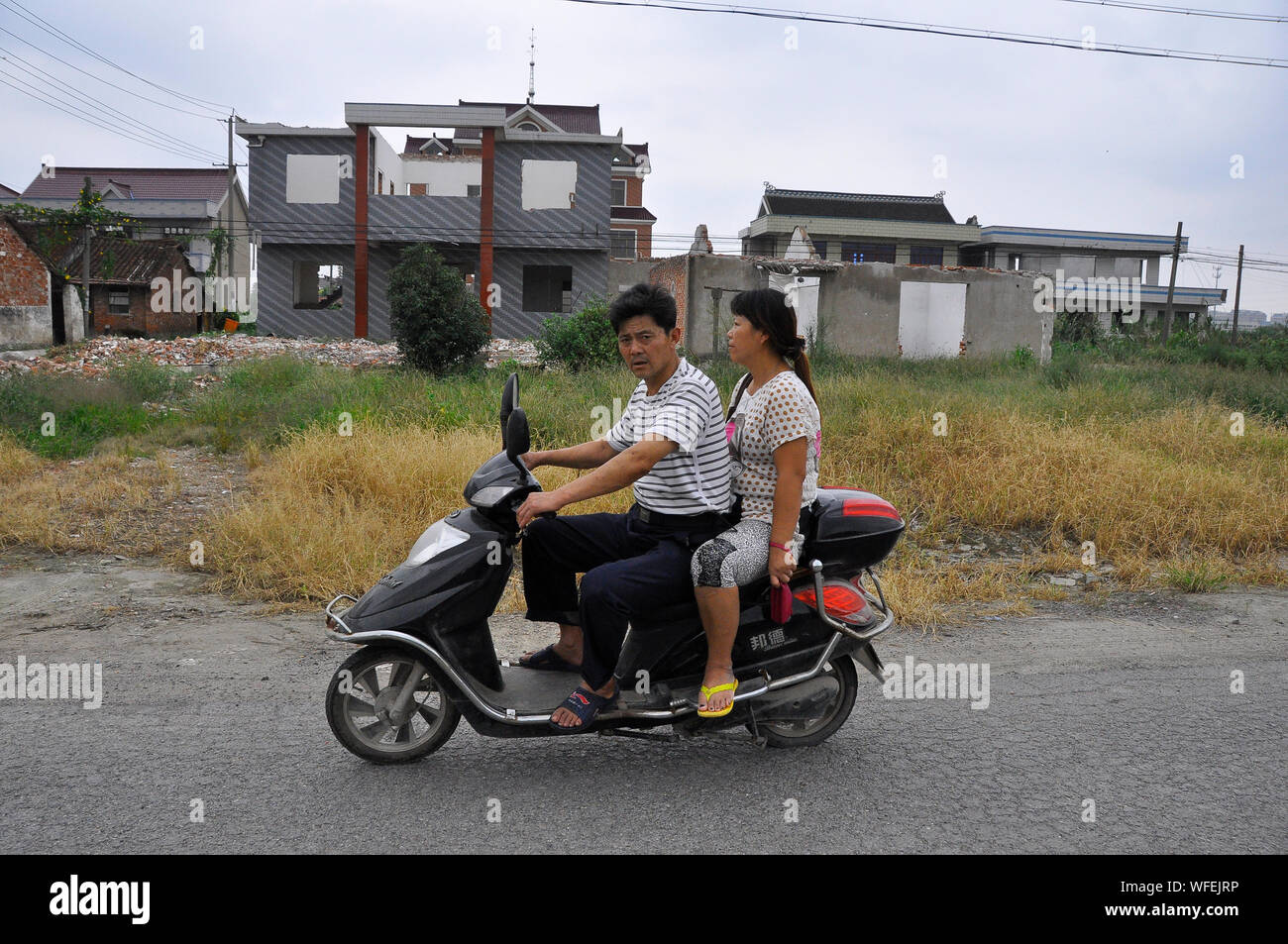 Il cinese e-bike rider viaggiare attraverso una zona che viene riproposto, Nantong Cina Foto Stock