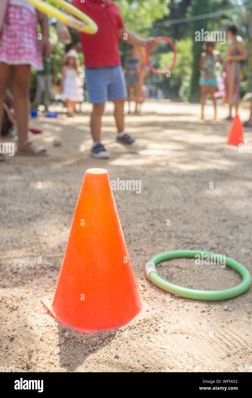 Bambini gettando anello colorato a cono nel parco. Classici giochi per bambini concept Foto Stock Bambini gettando anello colorato a cono nel parco. Classici giochi per bambini concept Foto Stock