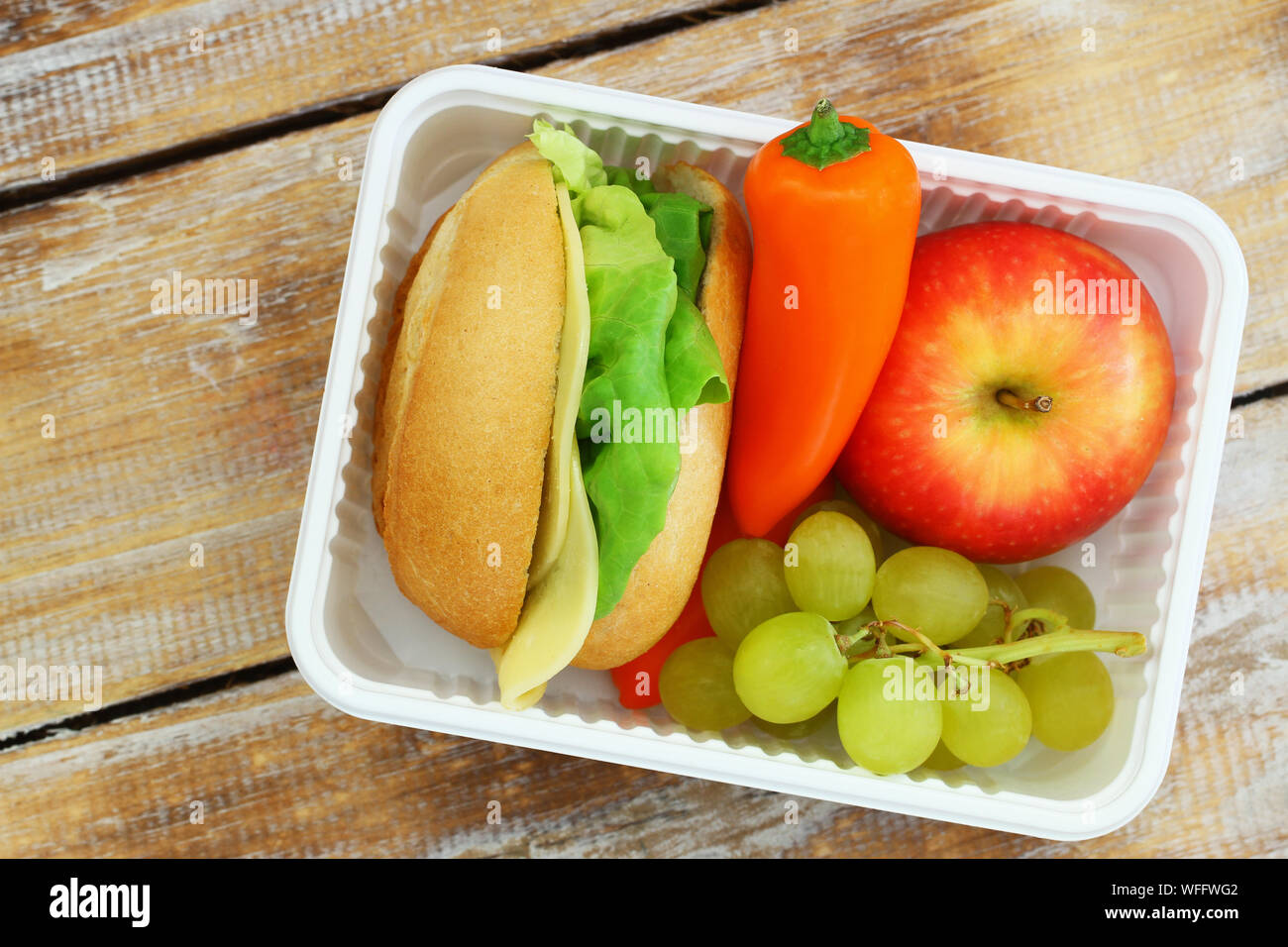 Una sana scatola di pranzo con formaggio rotolo, croccante di peperone giallo e frutta fresca Foto Stock