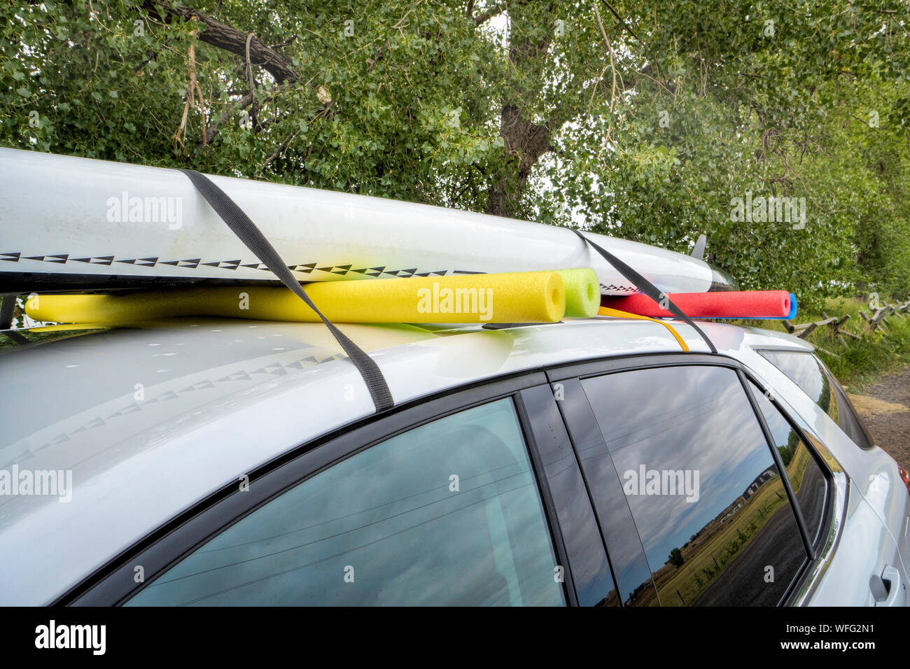 Stand up paddleboard su un auto a noleggio tetto, montaggio improvvisato con delle cinghie e piscina tagliatelle di schiuma Foto Stock