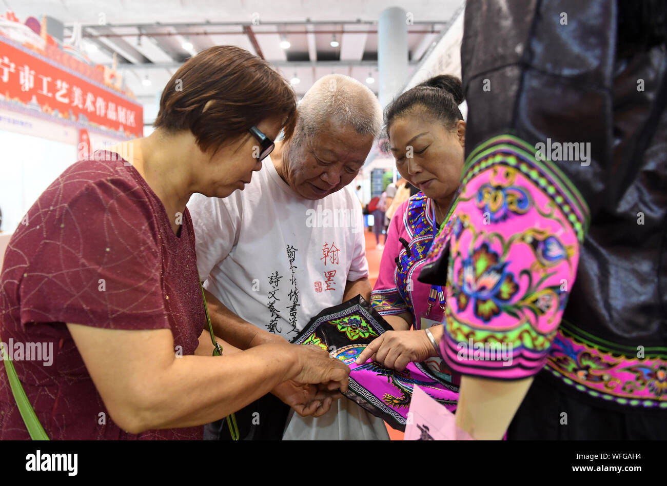 Nanning, della Cina di Guangxi Zhuang Regione autonoma. 31 Agosto, 2019. I visitatori a saperne di circa artigianalità di costumi folk a Nanning International Convention and Exhibition Centre in Nanning, sud della Cina di Guangxi Zhuang Regione autonoma, 31 Agosto, 2019. I quattro giorni di mostra su artigianato e opere d'arte di Guangxi calci fuori qui il venerdì, con circa 20.000 opere d'arte da più di 500 imprese, università, istituzioni e individui che viene visualizzata. Credito: Lu Boan/Xinhua/Alamy Live News Foto Stock